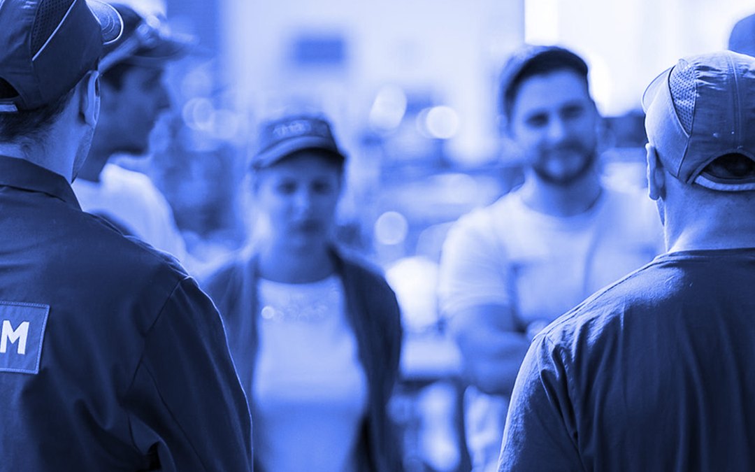 A team in work uniforms and caps talking together on site, tinted blue